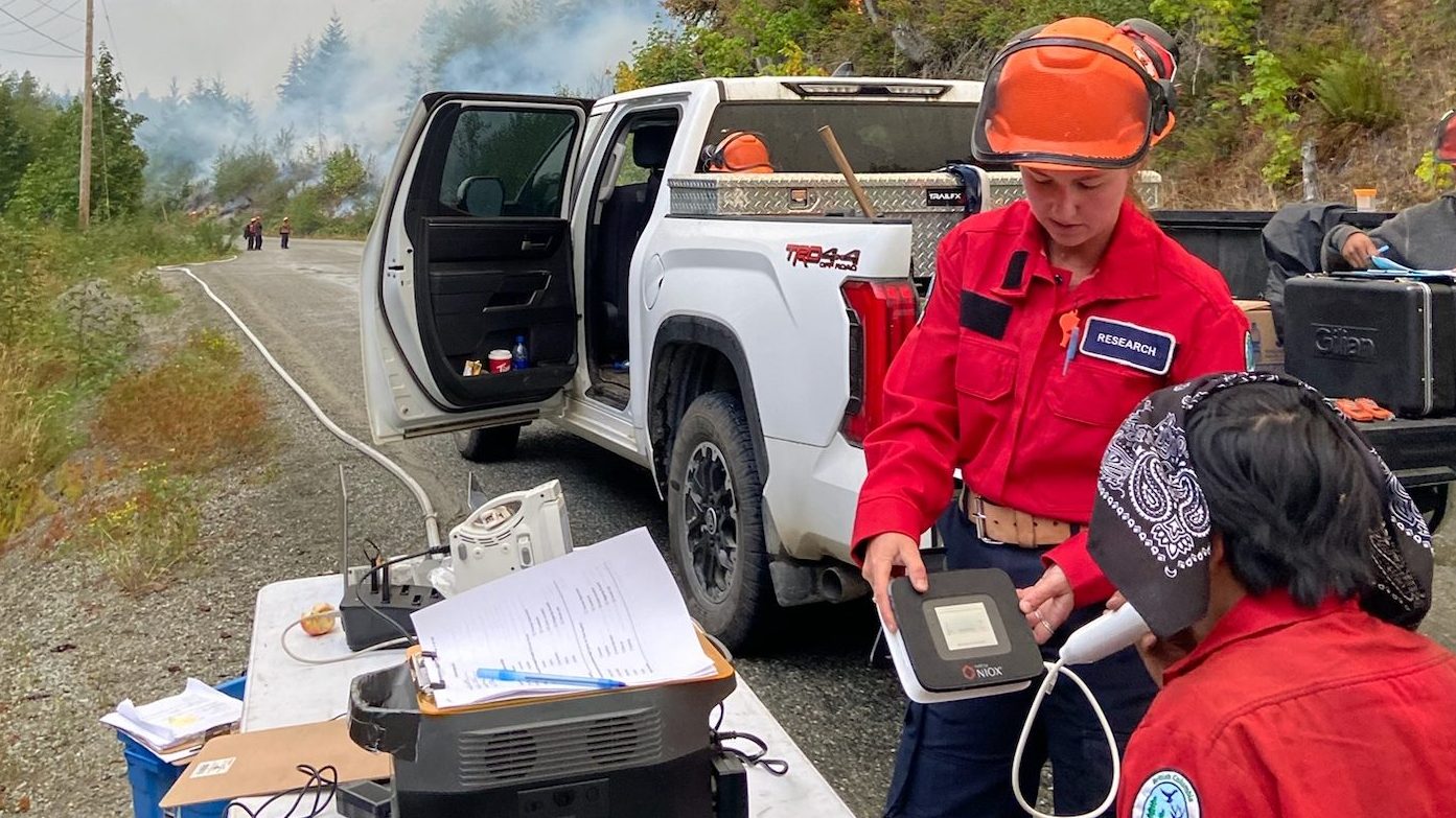 Dr. Madden Brewster conducts a post-shift lung function test with a Salish Unit Crew member on the Mount Underwood (V71498) wildfire in August 2025. The test measures nitric oxide in exhaled breath, an indicator of airway inflammation. These results are compared to pre-shift outcomes to help researchers understand how wildfire smoke exposure may affect cardiorespiratory health over the course of a shift.